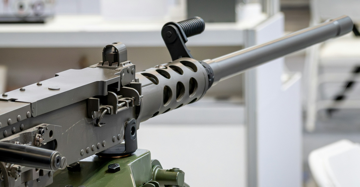 Heavy machine gun with ammunition belt on tripod.