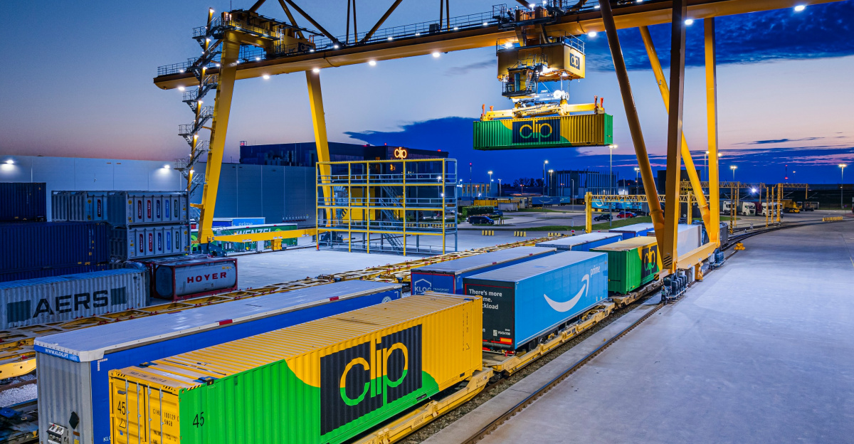 Gantry crane loading containers onto a train at dusk.