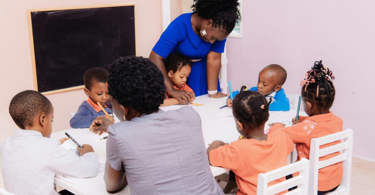 Teacher guiding children drawing at a table