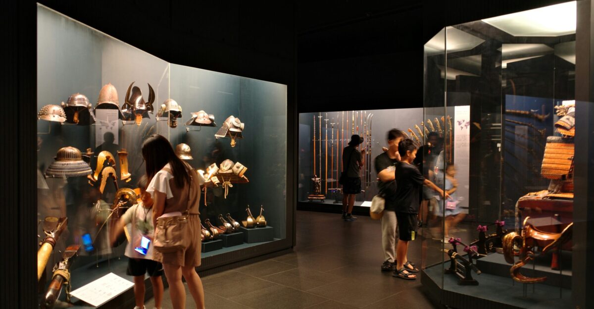 People viewing historical armor and weapons in a museum