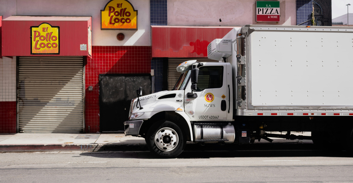 White truck parked on city street near businesses.