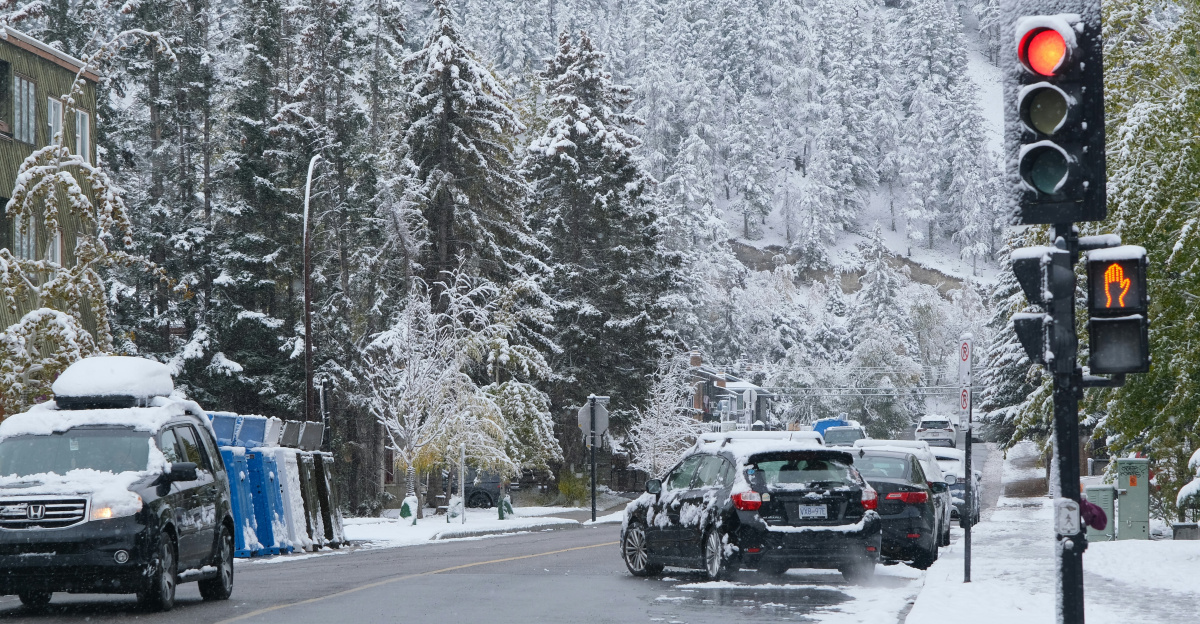 Traffic light on a snowy street with cars.
