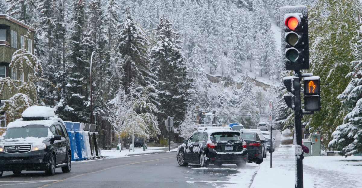 Traffic light on a snowy street with cars