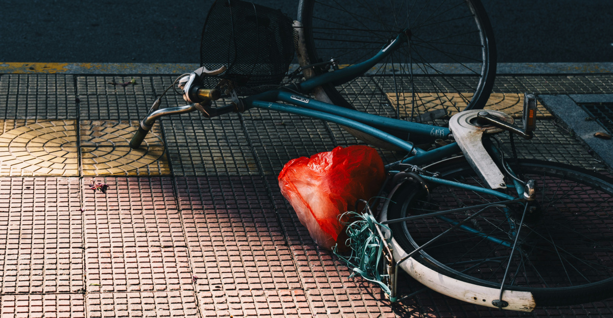 A bicycle lying on its side on a sidewalk.