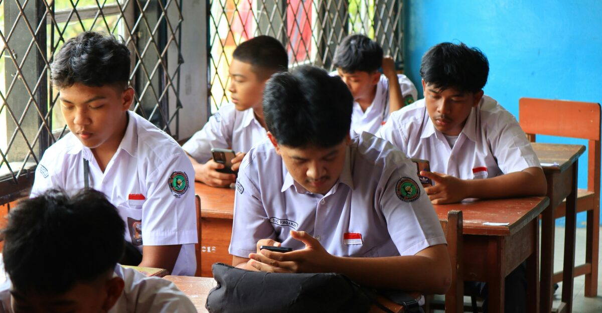 Students in uniform using phones in classroom