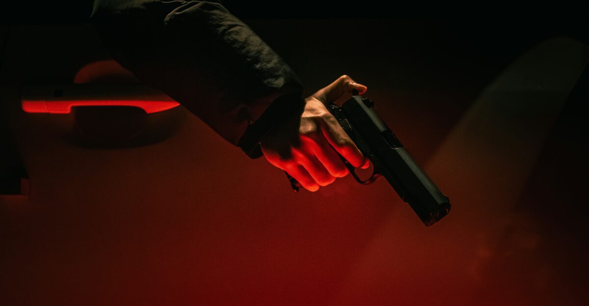 Hand holding a gun near a car door