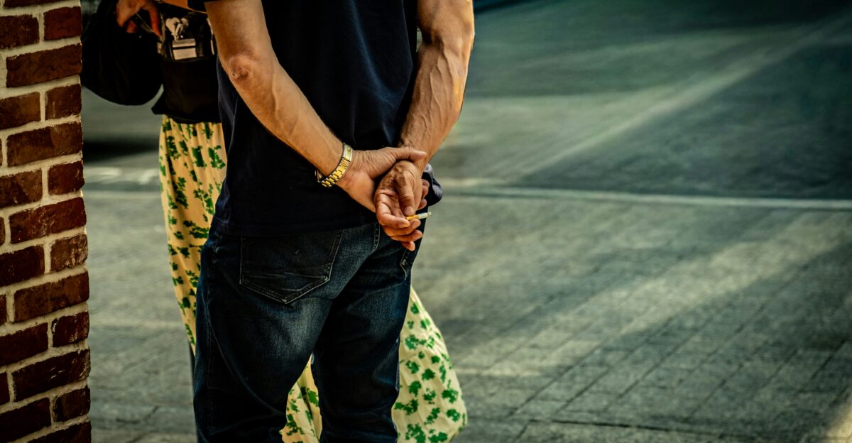 Two people stand near a brick wall outdoors