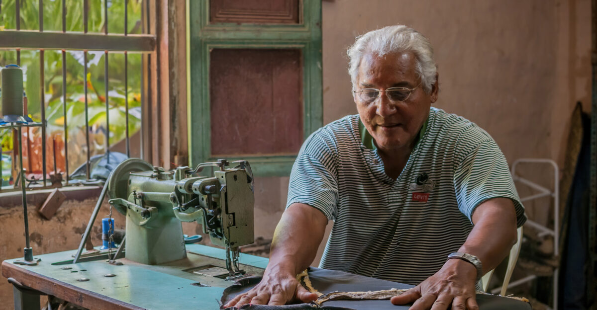The image shows an elderly man with Hispanic features sitting in front of the window of his bahareque house a type of traditional construction in Venezuela made of mud and other natural materials The soft daylight enters through the window illuminating the makeshift workspace where the man with a calm and focused expression dedicates himself to sewing the upholstery of his car The sewing machine an old Singer model stands out in the foreground with its classic design and handwheel that has been adapted with a washing machine motor under the table The upholstery that the man is repairing shows signs of wear but also care symbolizing effort and dedication in times of scarcity In the background the bahareque walls with their earthy texture and marks of the passage of time speak of the resilience of the structures and the people who inhabit them This photograph taken a decade ago is a testament to hope and human tenacity at a time when self-management became an everyday response to economic adversity More than a simple capture of a moment in an individual s life it reflects the shared history of a community that even in difficult times clings to the hope for better days