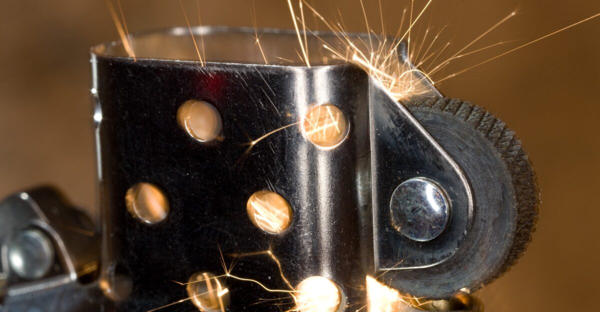 Shot with and MP-E 65 at 1x minimum magnification f16 15s exposure in dark room long exposure to allow time for the spark while letting the finger disappear Lit with a ringflash M 1 64 for fill and a handheld 580 EX II Manual 1 128 zoom 105mm fired 4 times handheld three against the background to give the smokey look and one from above right to add some detail to the wheel and inside of the lighter No postprocessing - straight through lightroom default settings