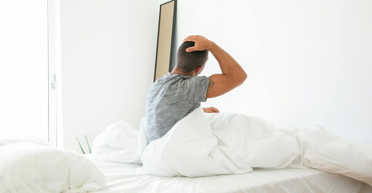 A man stretches in bed during a bright morning starting his day