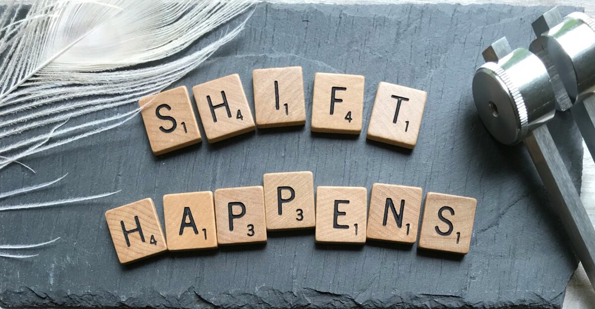 scrabble chips forming shift happens word near white feather