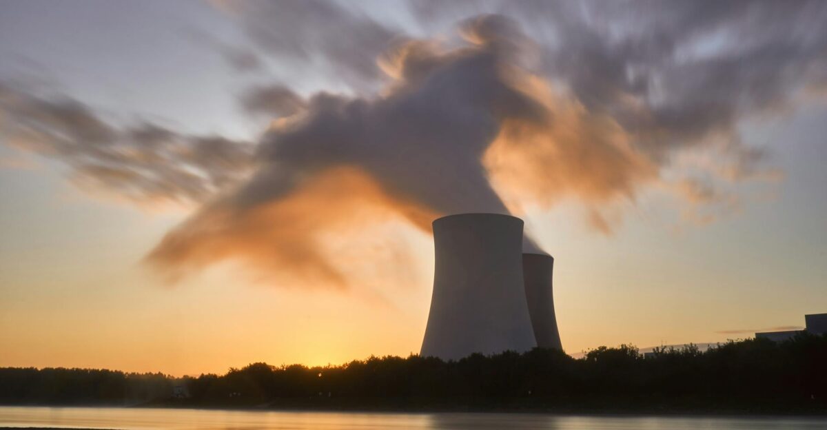 Dramatic image of a nuclear power plant at sunrise with steam rising into a colorful sky